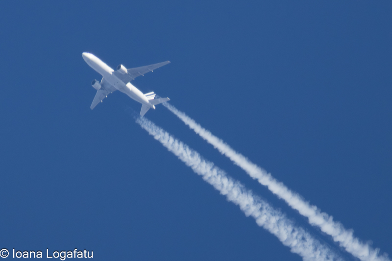 Airplane soaring high, leaving trails in sky